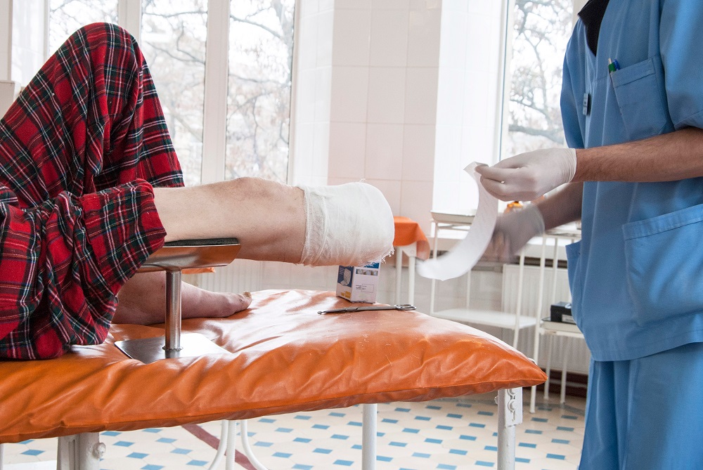 Nurse changing bandage on patient with amputated leg,