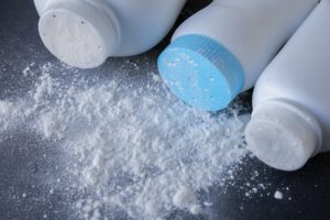 Talcum powder that caused ovarian cancer scattered on black table.