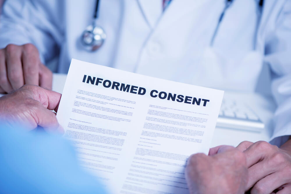 Patient reading an informed consent document in front of doctor.