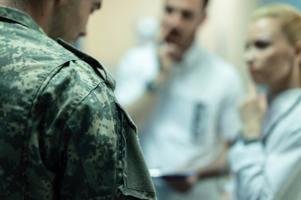 Close up of veteran with two doctors in the background at clinic.
